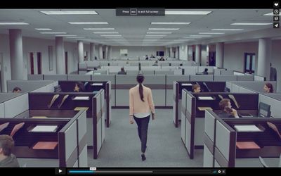 a woman walking through a room filled with cubicles