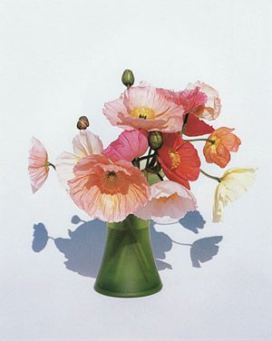 a green vase filled with pink and orange flowers