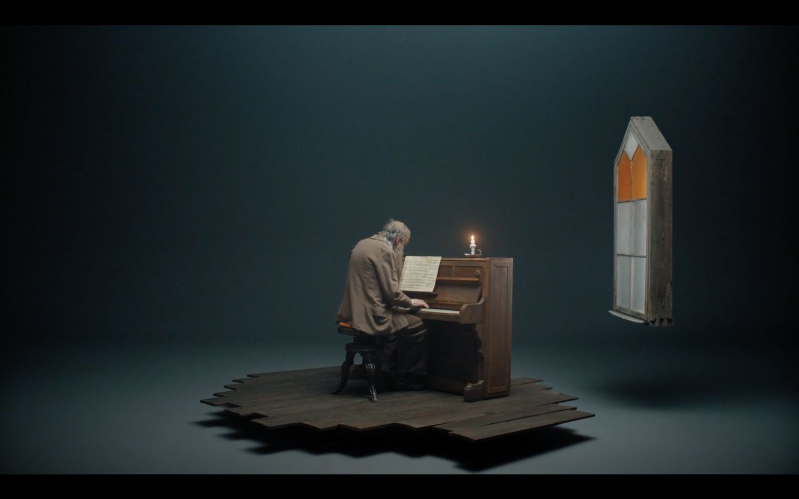 a man sitting at a piano in front of a lit candle