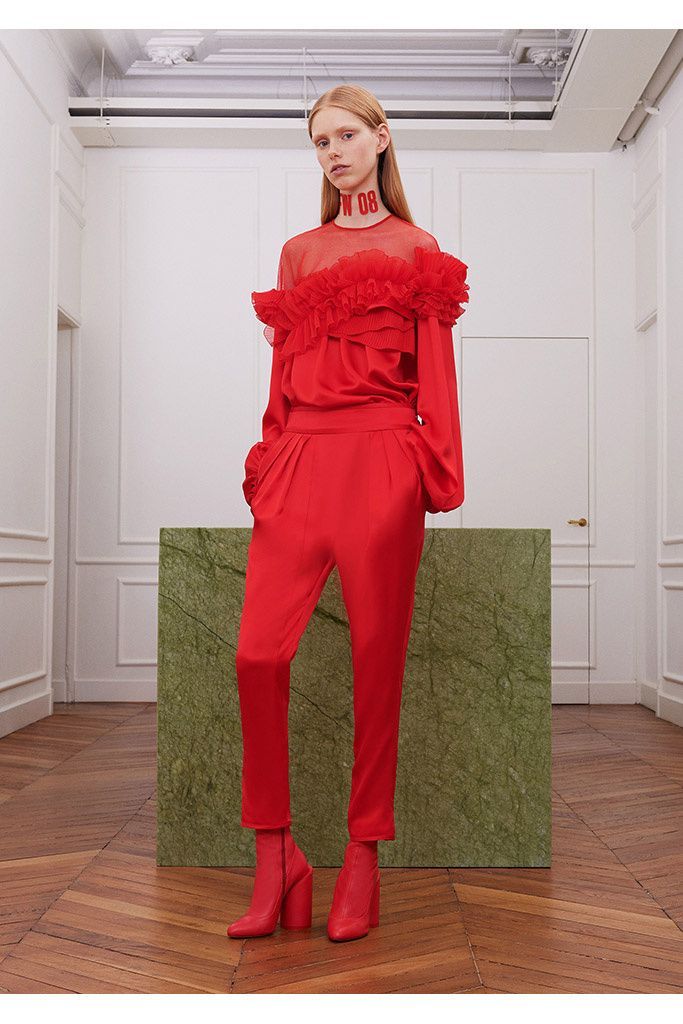 a woman in a red jumpsuit standing in a room