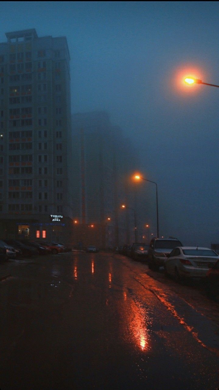 a city street at night with cars parked on the side of the road