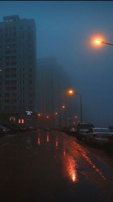 a city street at night with cars parked on the side of the road