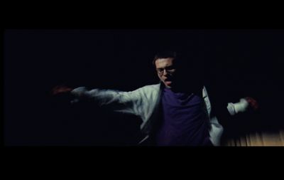 a man in a white jacket is dancing in the dark