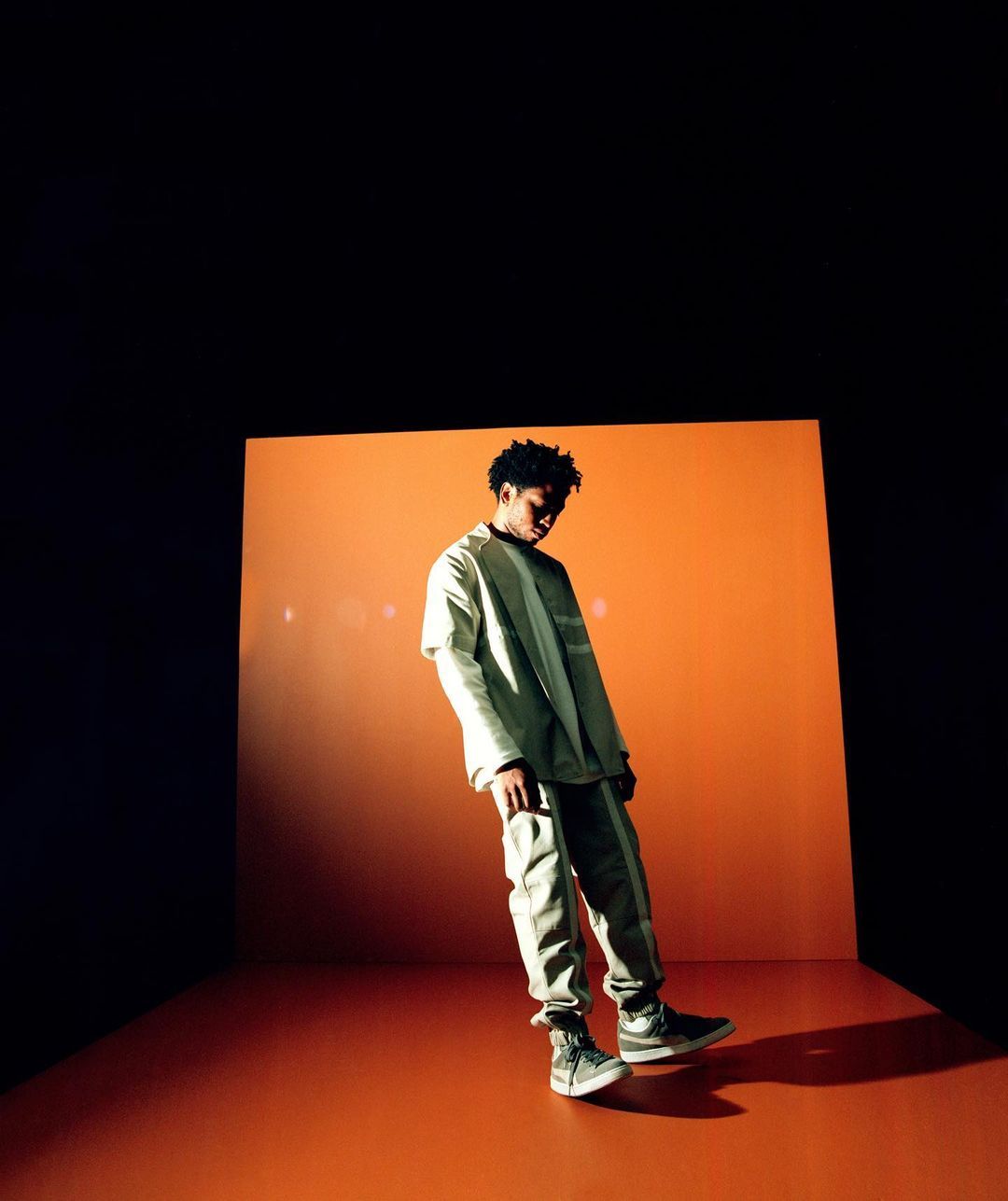 a man standing in front of an orange wall