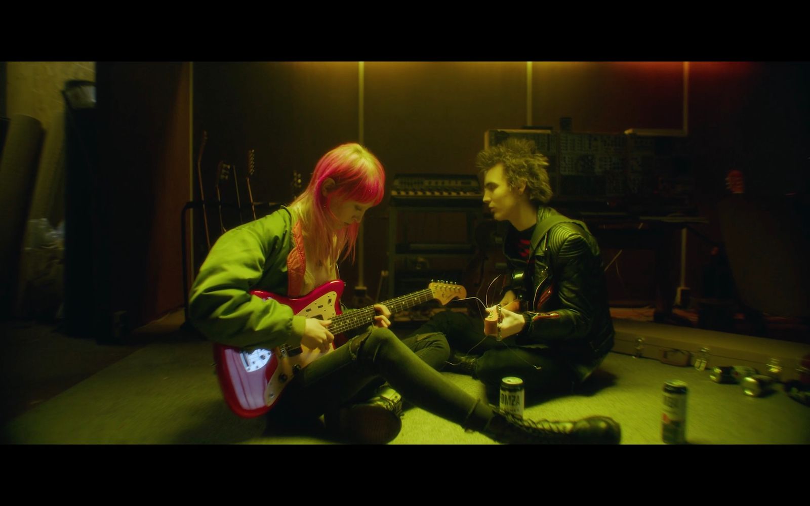 a man and a woman sitting on the floor playing guitars