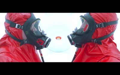 two people wearing red and black gas masks