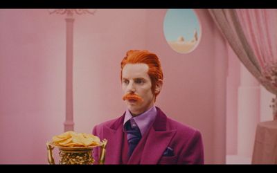 a man in a purple suit holding a golden cup