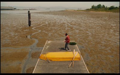 a man standing on a dock next to a yellow boat