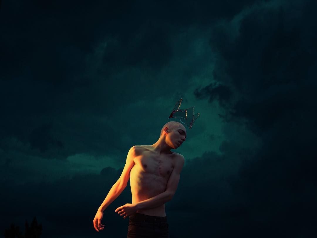 a man with a crown on his head standing in the dark