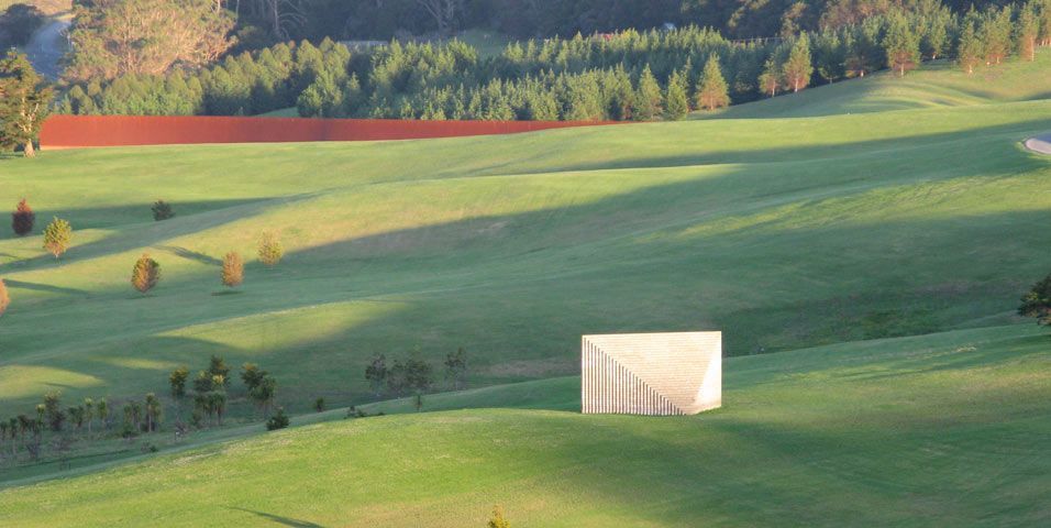 a green field with a white structure in the middle of it