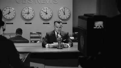 a man sitting at a desk in front of clocks