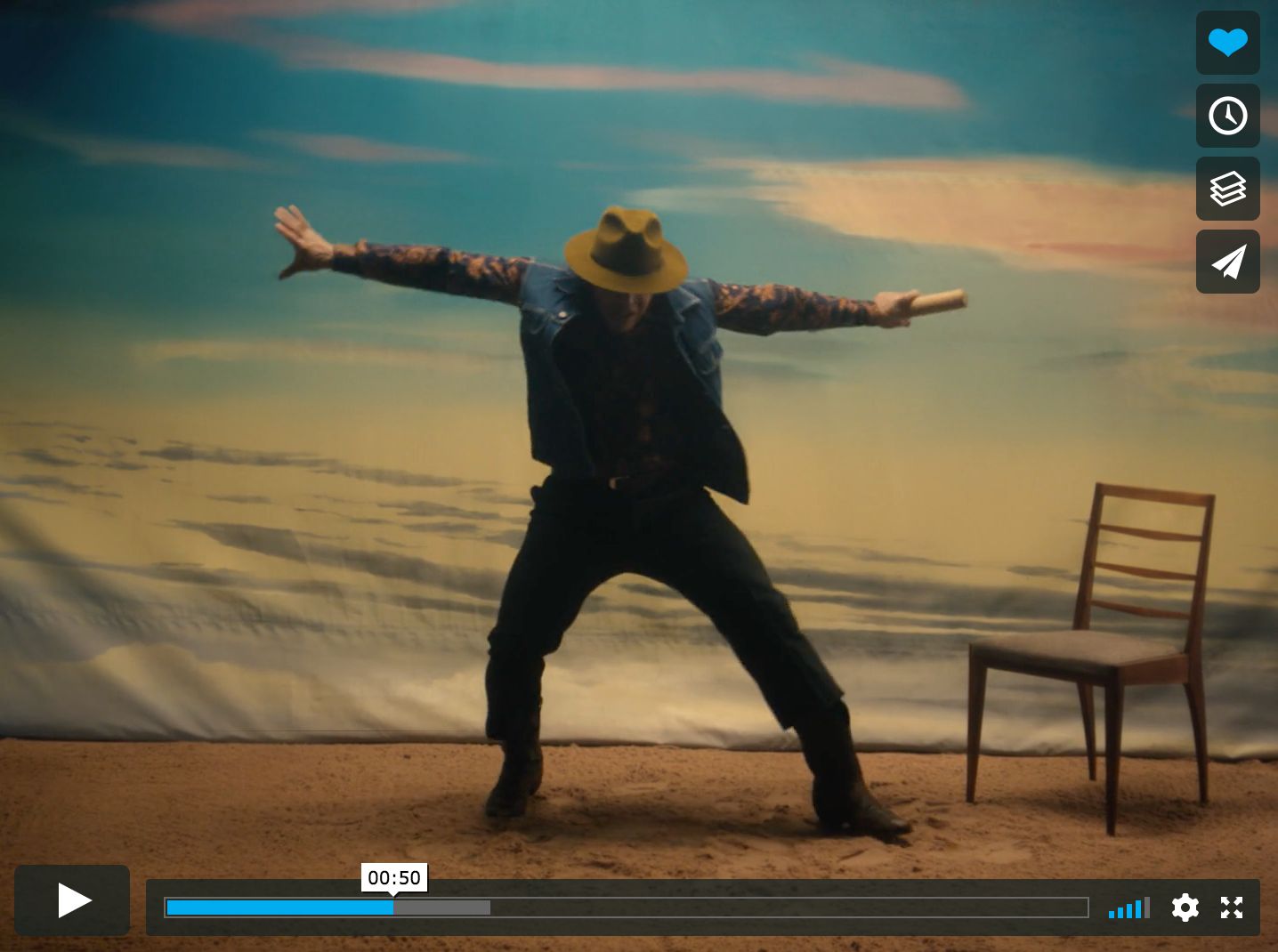 a man in a cowboy hat standing in front of a chair