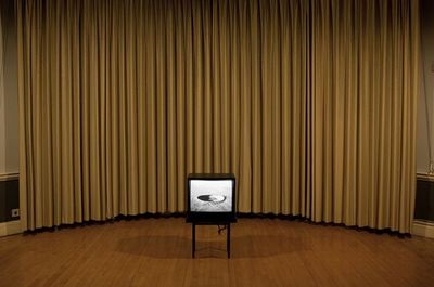 a television sitting on a stand in front of a curtain