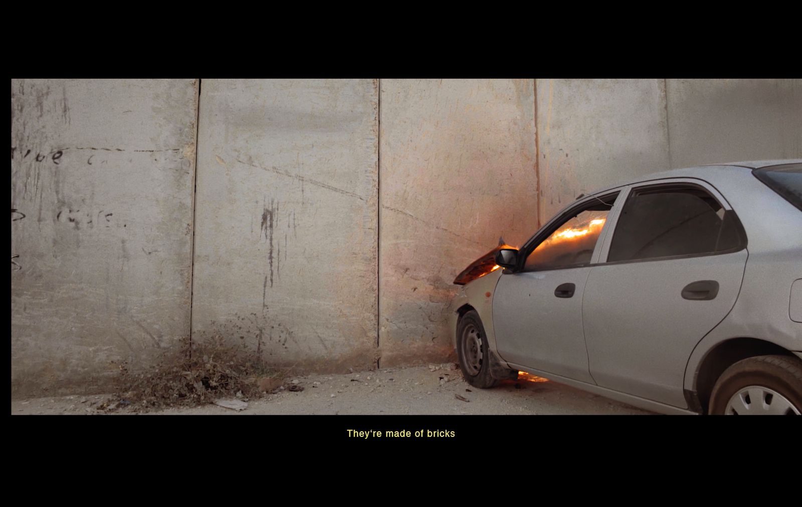 a small white car parked next to a wall