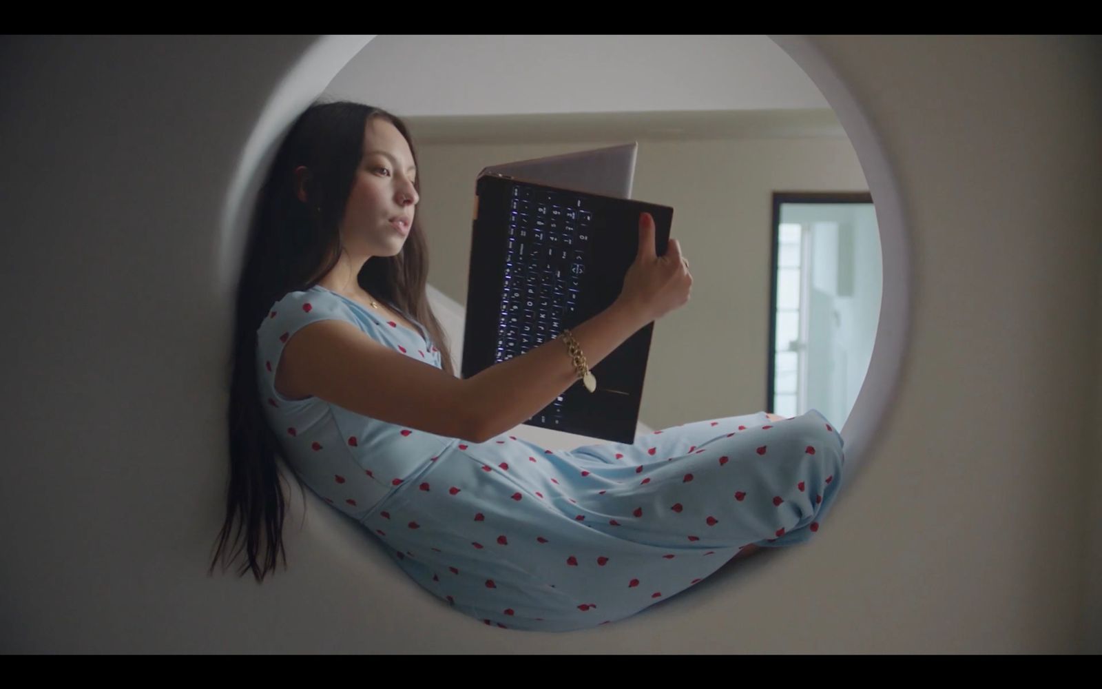 a woman sitting on a wall holding a laptop