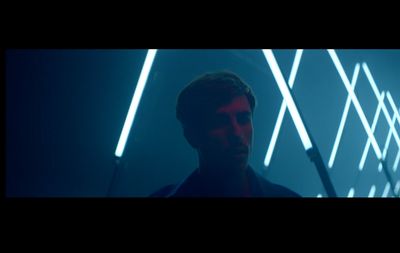 a man standing in front of a wall with neon lights