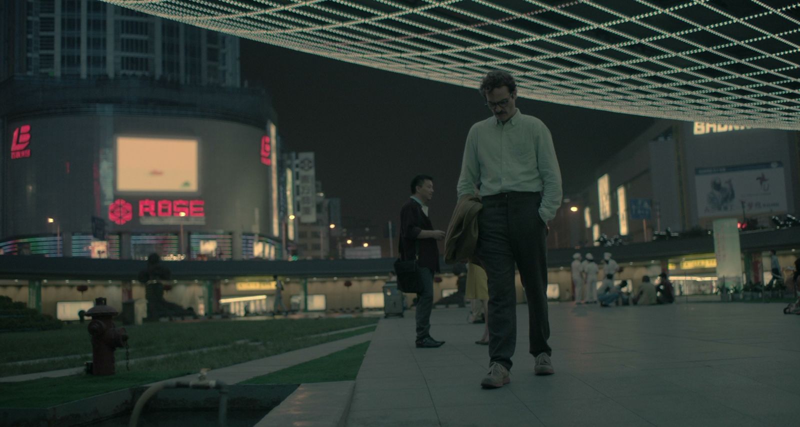 a man walking down a sidewalk in a city at night