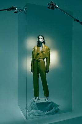 a mannequin dressed in a yellow suit in a glass case