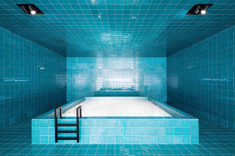 a blue tiled bathroom with a ladder leading up to the bathtub