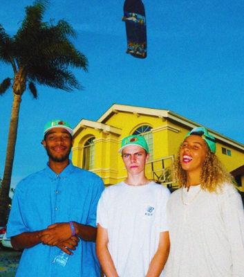 three people standing in front of a yellow building