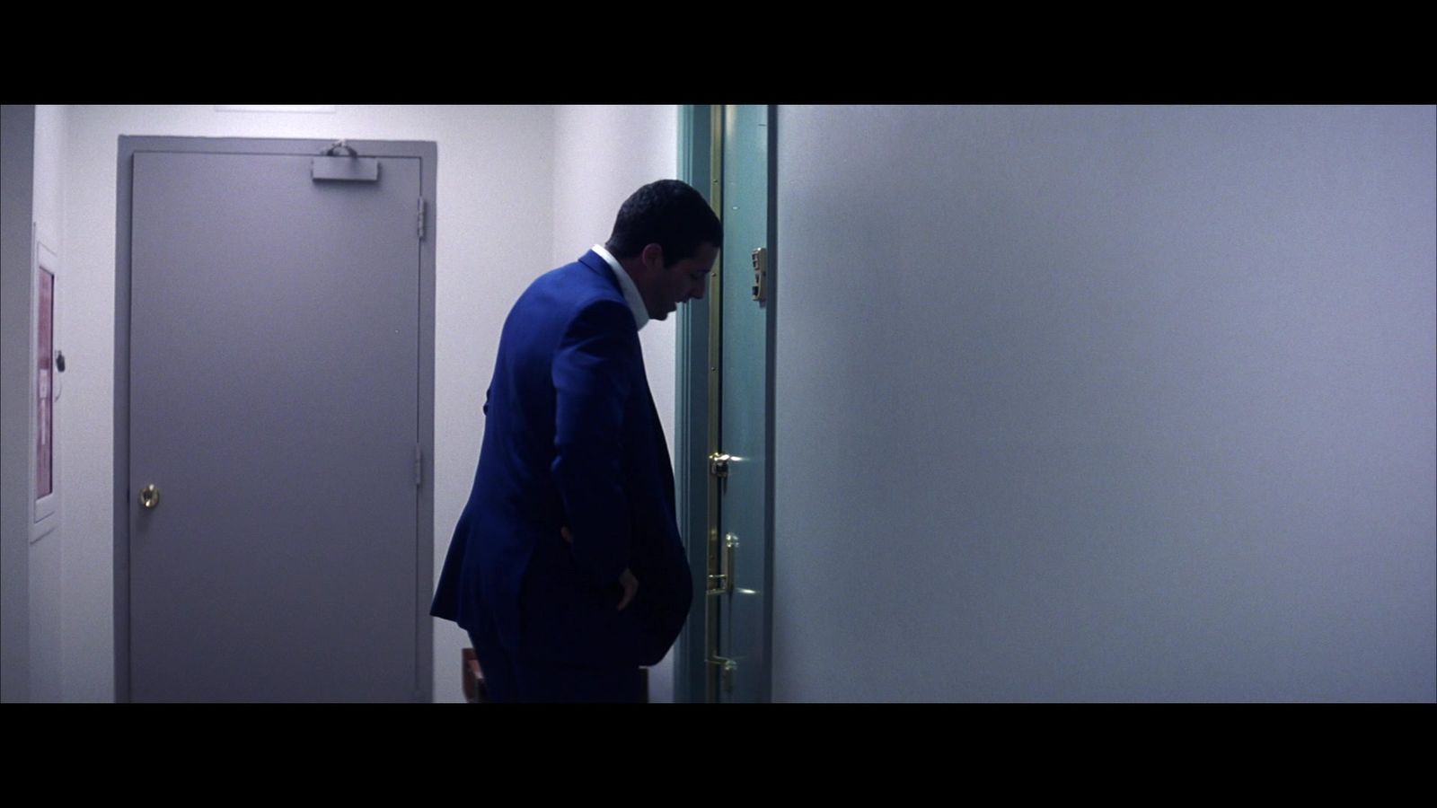 a man in a blue suit standing in front of a door