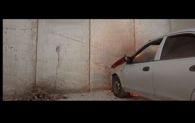 a white car parked next to a concrete wall