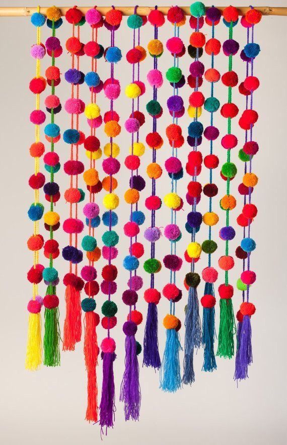 a multicolored wall hanging with pom poms