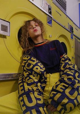 a woman laying on top of a dryer next to a yellow wall