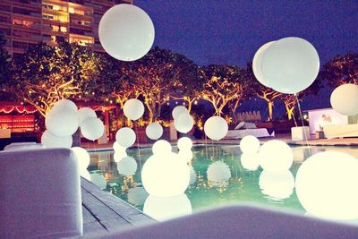 a group of white balloons floating over a swimming pool