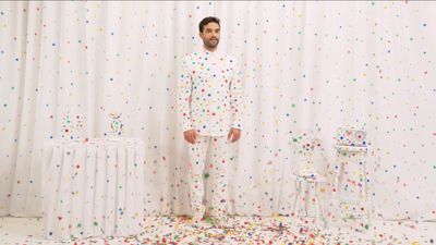 a man standing in front of a curtain with confetti all over it