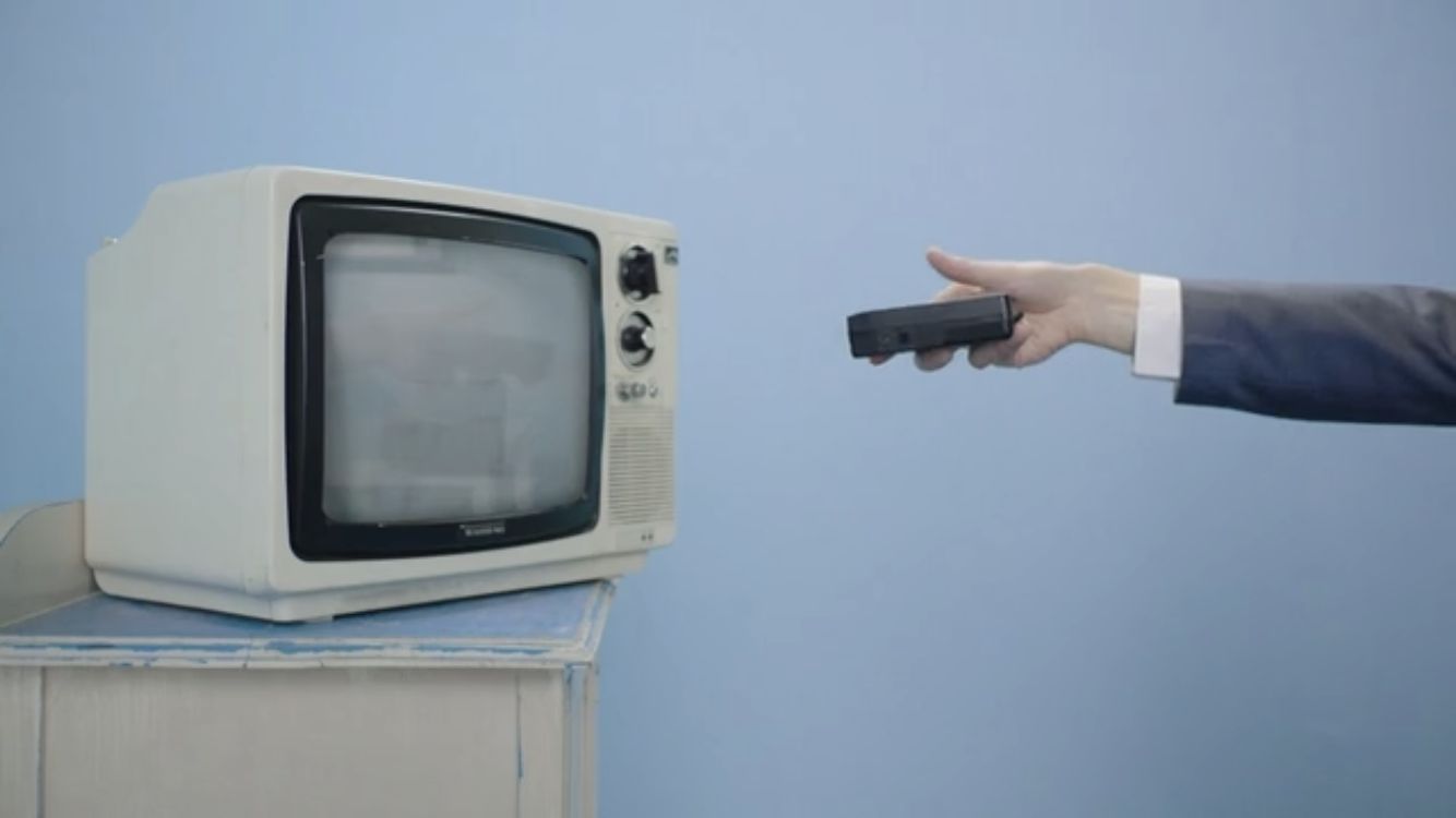 a person in a suit pointing a remote at a television