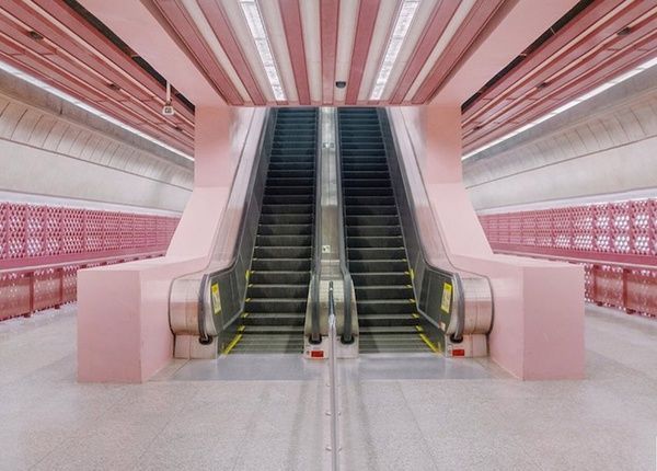 an escalator in a building with pink walls