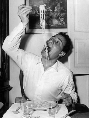 a man sitting at a table eating spaghetti