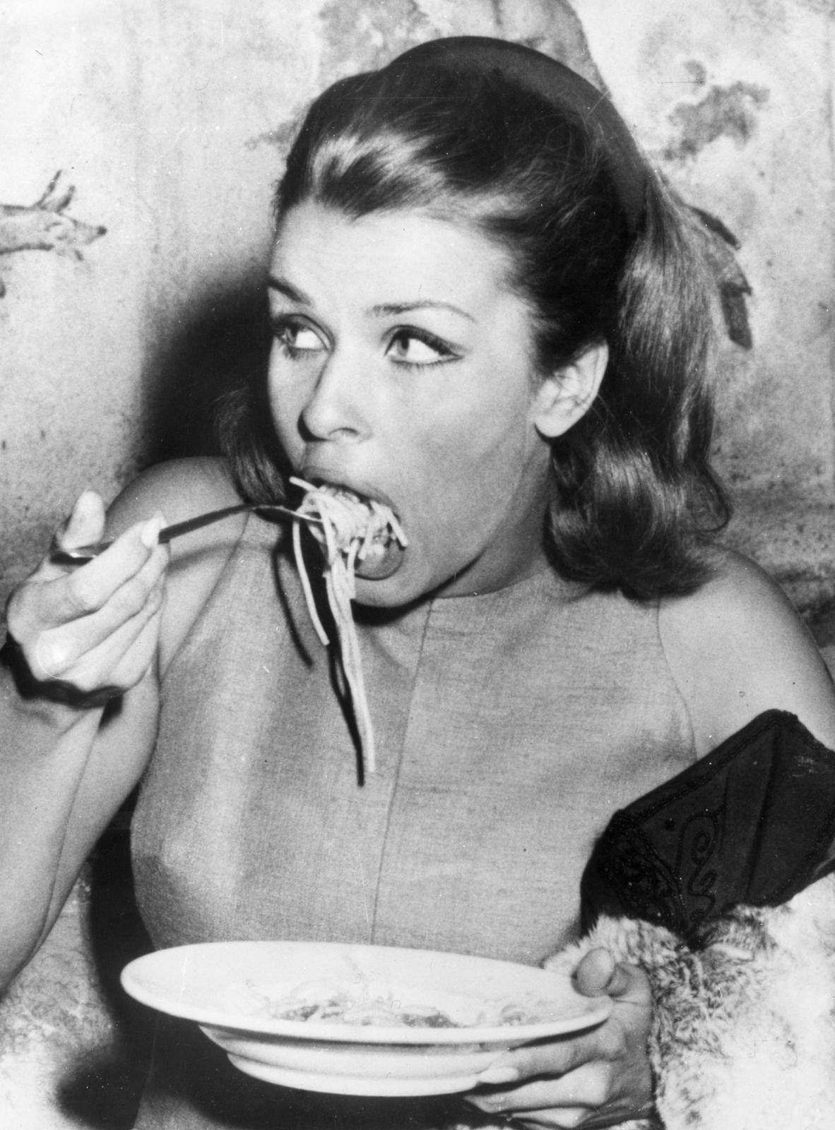 a woman eating spaghetti off of a plate