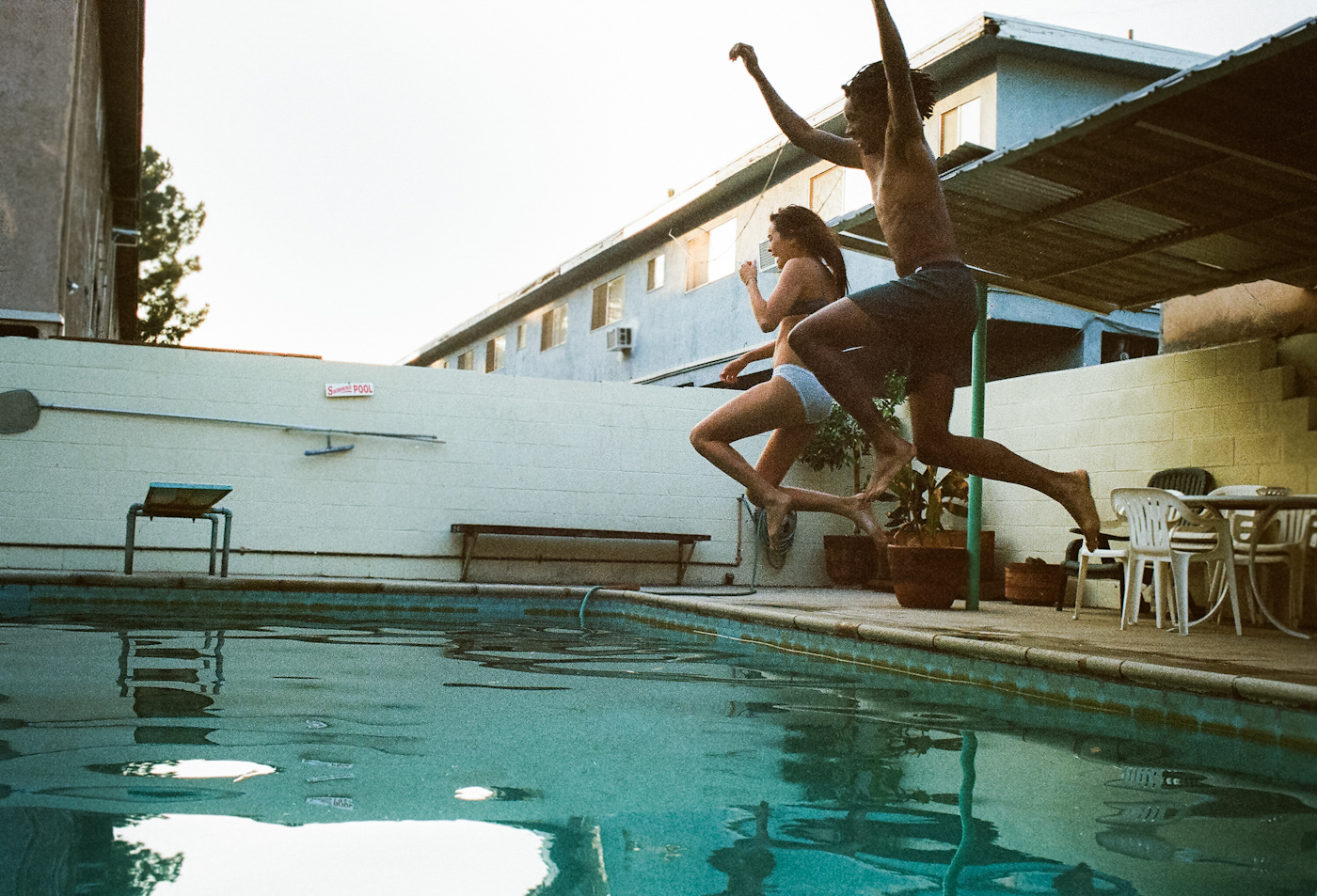 a couple of people jumping into a swimming pool