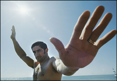 a man standing on a beach holding his hand up in the air