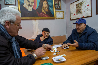 a group of older men playing cards at a table