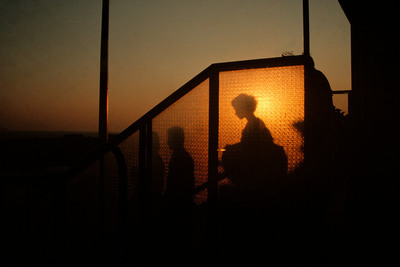 a silhouette of a person standing in front of a gate