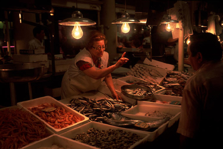 a woman standing in front of a table filled with lots of food