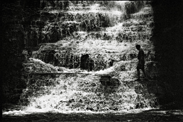 a man standing in front of a waterfall