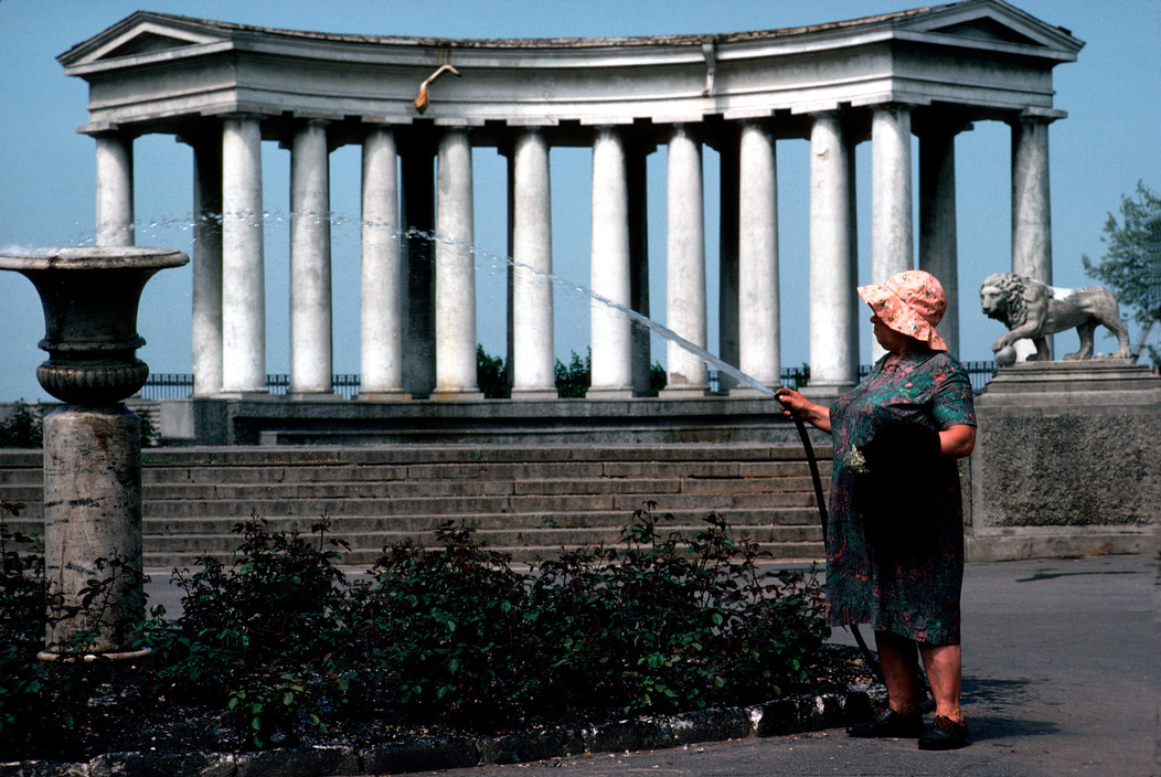 a woman standing in front of a fountain with a hose