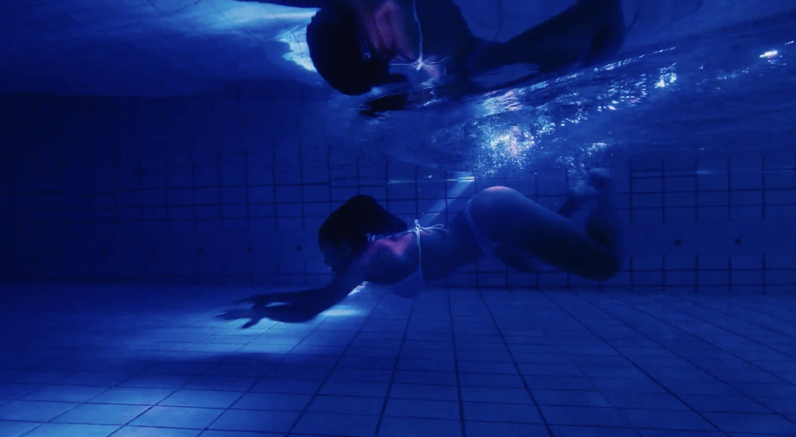 two people swimming under water in a pool