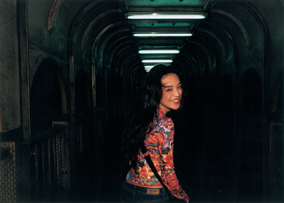 a woman standing in a tunnel with a handbag on her shoulder