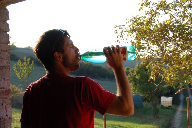 a man drinking water from a green bottle