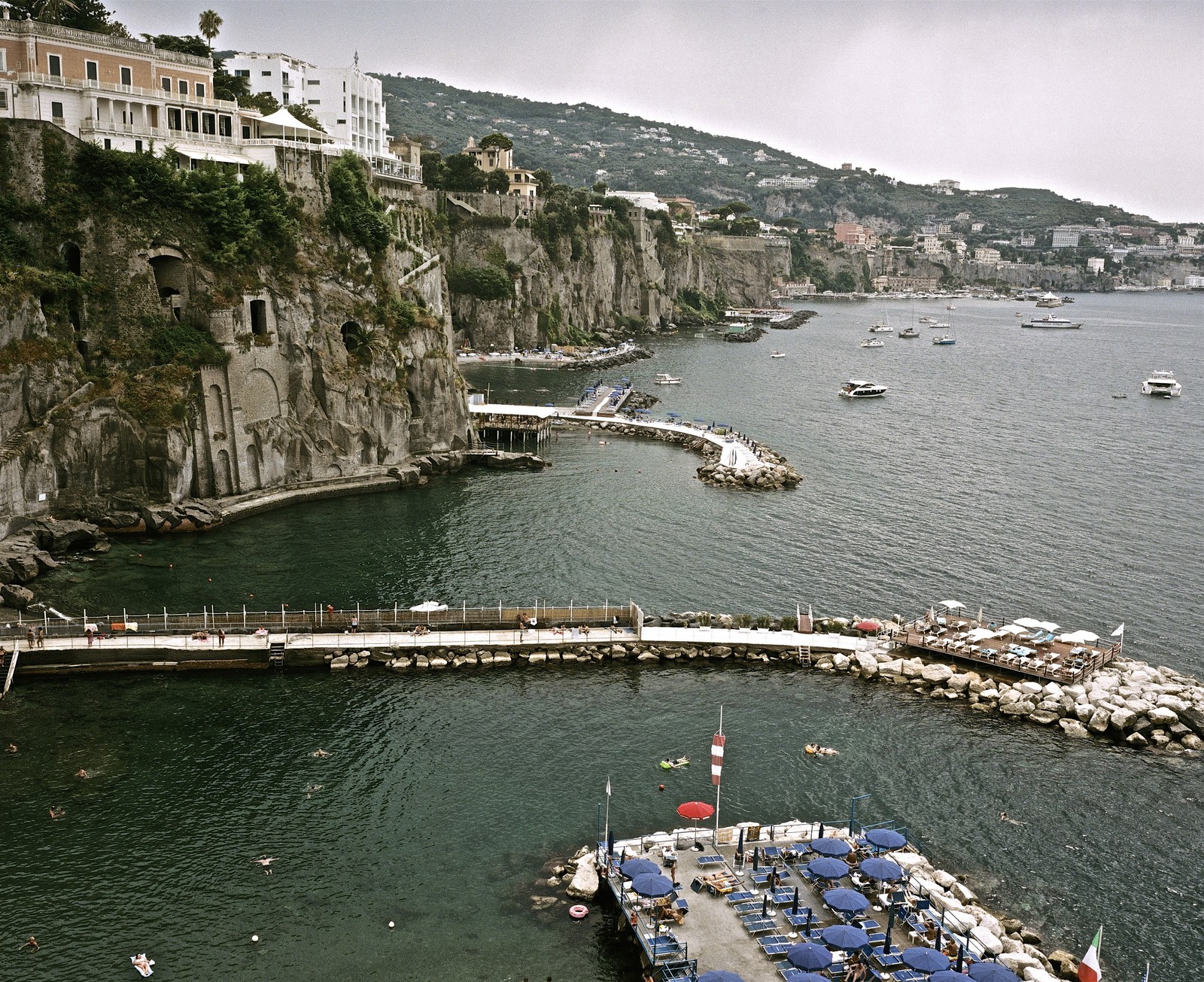 a harbor with boats and a pier with umbrellas