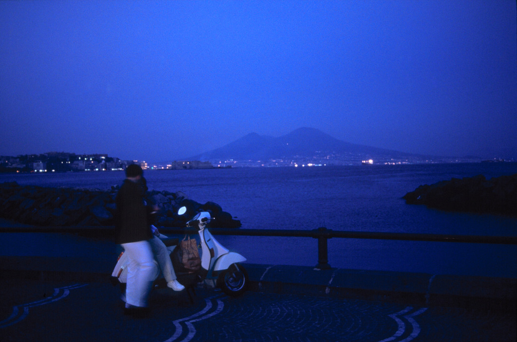 a person standing next to a scooter near a body of water