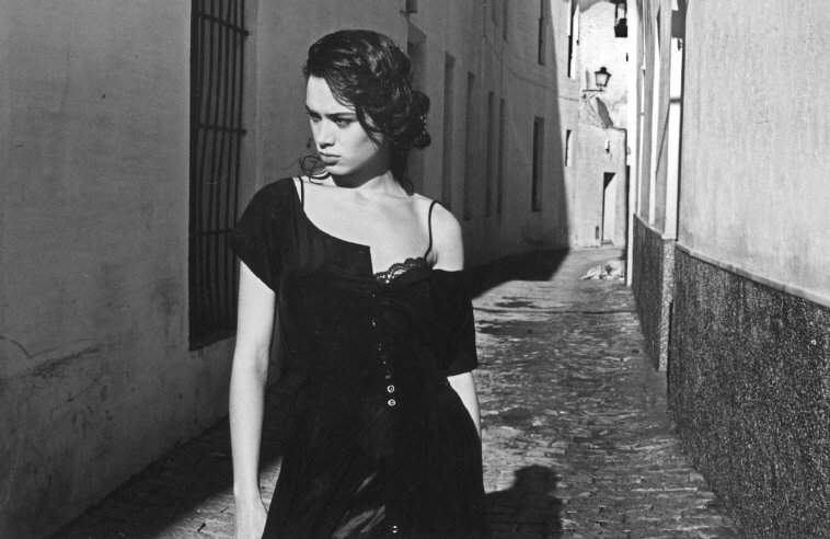 a woman walking down a street next to a building