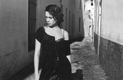 a woman walking down a street next to a building