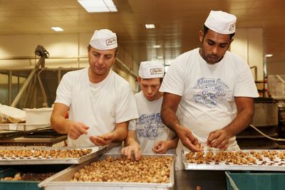 a group of men standing next to each other in front of trays of food