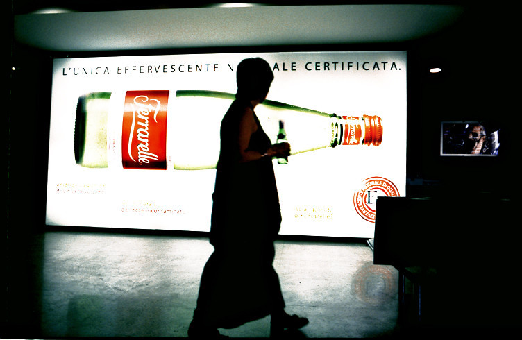 a man walking past a coca cola advertisement